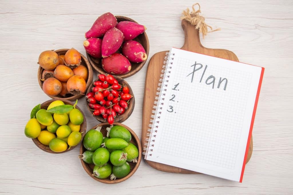 Plan nutritionnel personnalisé accompagné de fruits frais, symbolisant une alimentation équilibrée et durable.