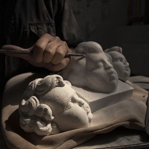 Sculptor carving a baroque putto in marble