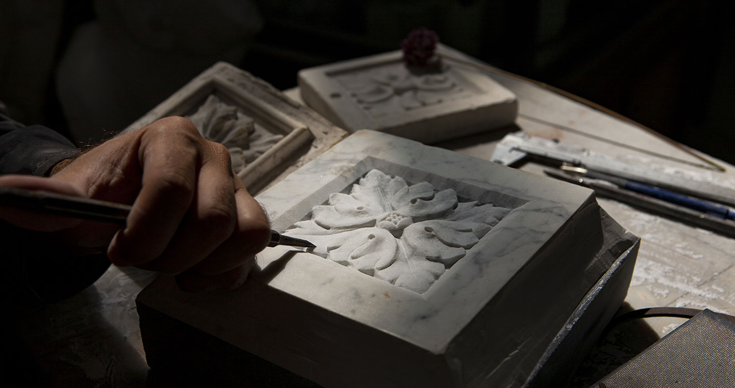 Sculptor carving a flower ornament in marble