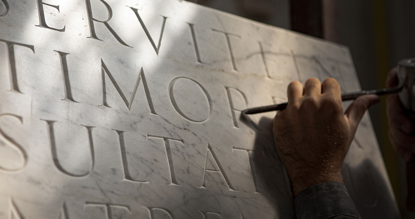 Sculptor carving letters on marble