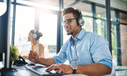 Cropped shot of a handsome young man working in a call center with a female colleague in the background
