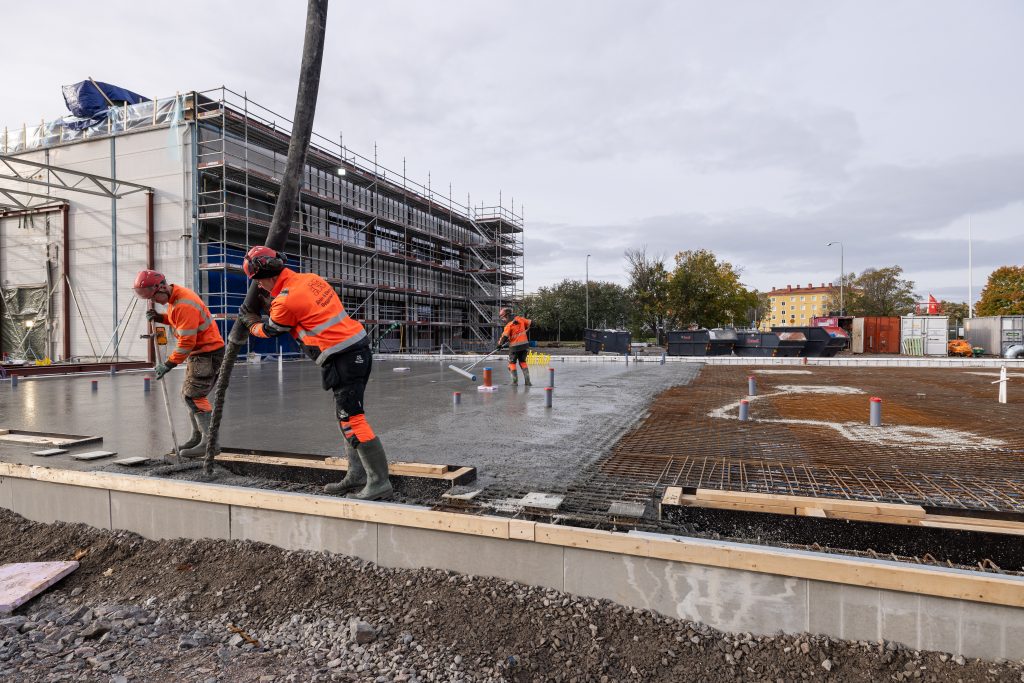 Tre medarbetare från Åhlin & Ekeroth Byggnads AB arbetar med att gjuta betongplatta för Rejmes nya bilanläggning i Norrköping. 