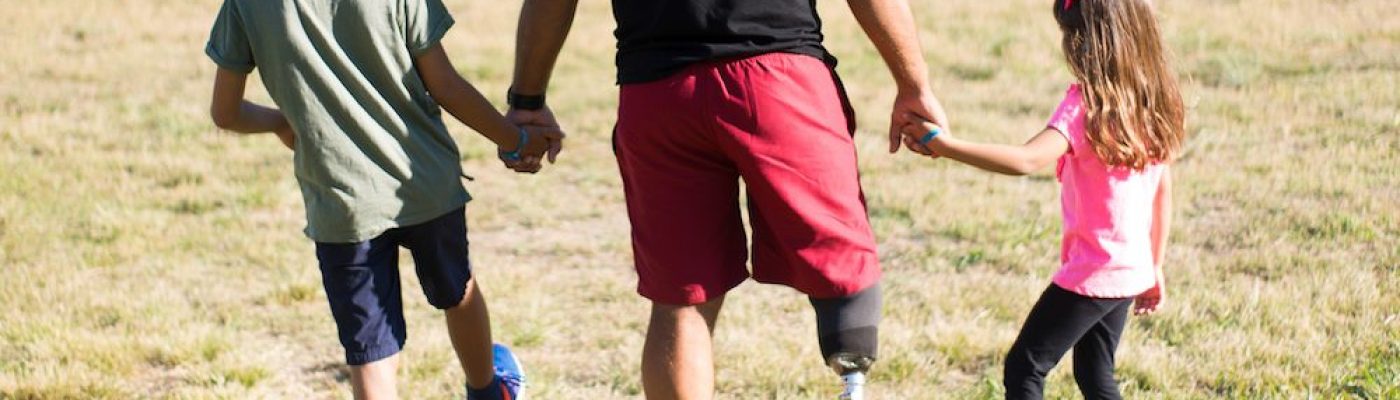 Back view of happy father with disability walking with children Back view of happy father with disability walking with children. Man with mechanical leg having walk in park with boy and girl. Disability, family, love concept