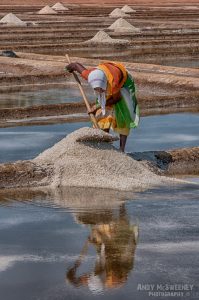 Portrait of a colourful salt pan worker shovelling salt up in a pile in the salt fields of Gokarna, South-India 2010