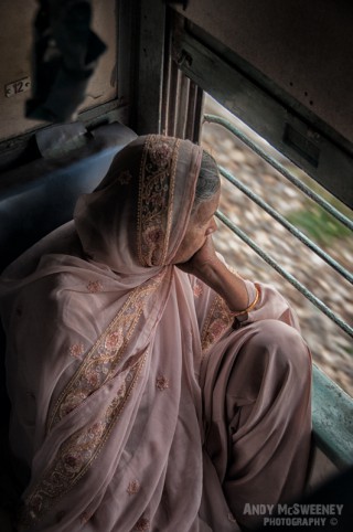 Portrait of an old Indian lady in sari looking out the window on a train in South-India