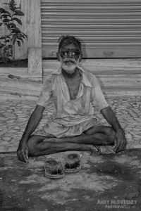 Black and white portrait of an Indian untouchable man with sunglasses in yoga pose on the streets of South-India, Mumbai