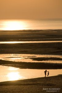 Boy walking the beach at sunset in Zeeland, The Netherlands