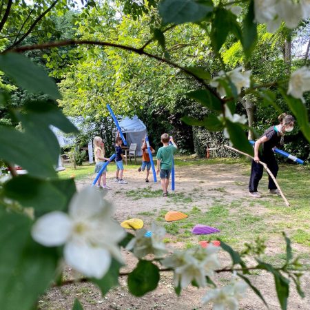 Kinderen en vrouw die buiten met blauwe slingers spelen.