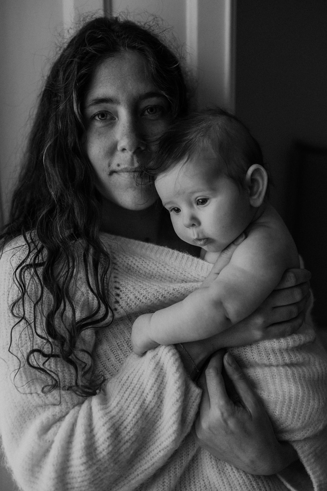 mamma sitter med sin bebis i stickad tröja