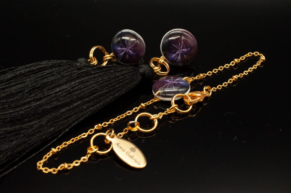 Ein Paar dunkelviolette Ohrringe mit einem passenden Armband