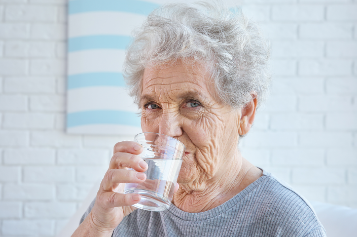 Äldre person dricker vatten