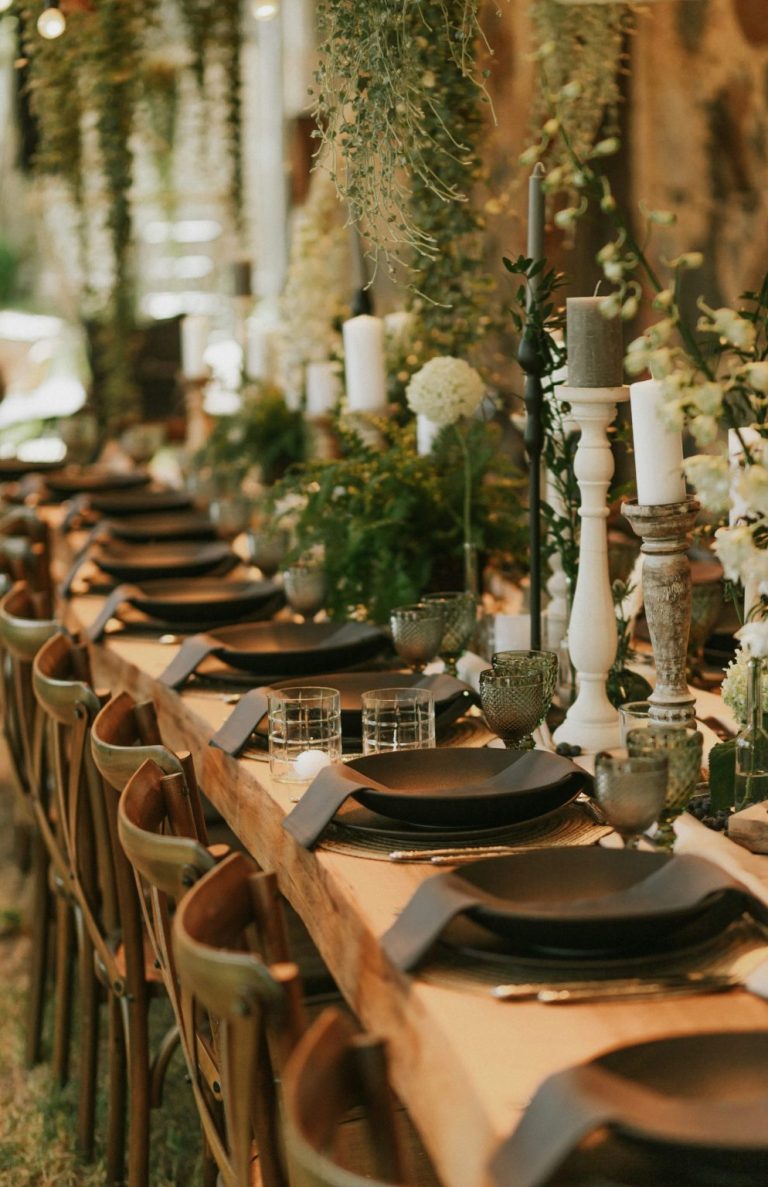 Elegant bordopstilling med sorte tallerkener, lys og blomster til fest