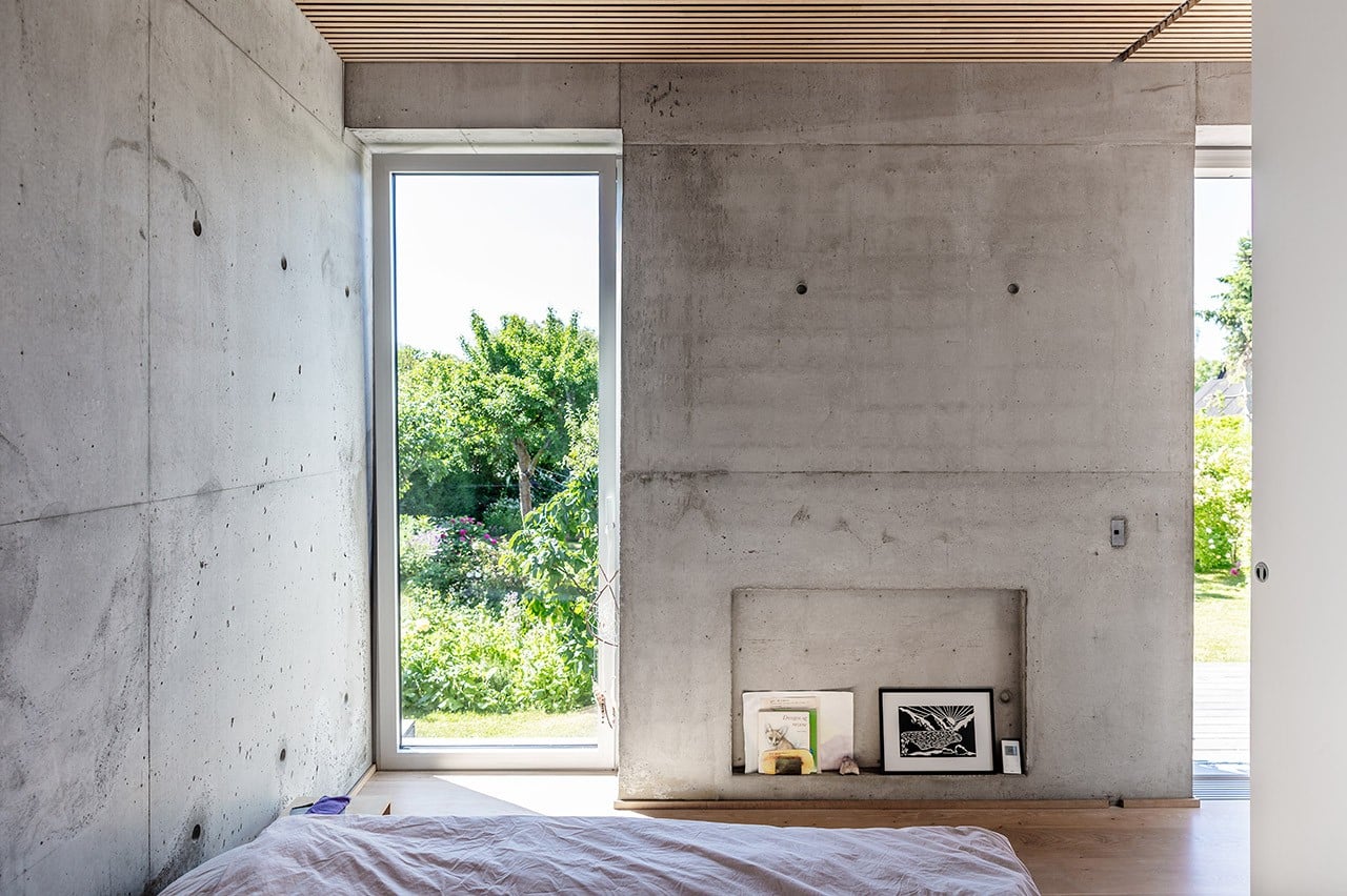 Soveværelse med zen-stemning, rå betonvægge og fantastisk udsigt til haven