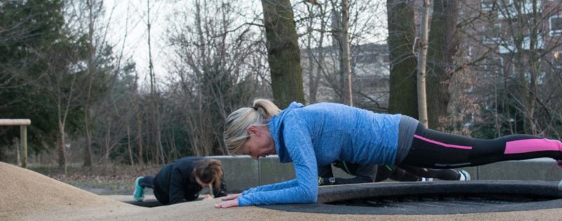Kvinder, der udfører planke-øvelsen under udendørs træning, i søndermarken