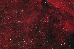 The bipolar planetary nebula Hen 2-169 and the Wolf-Rayet ring nebula PCG 11 against a vast expanse of red H-alpha emission. An astrophotographic image taken in the constellation Norma from the Gemsbock Observatory in Namibia.