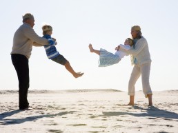 Besteforeldre leker med sine barnebarn på stranda