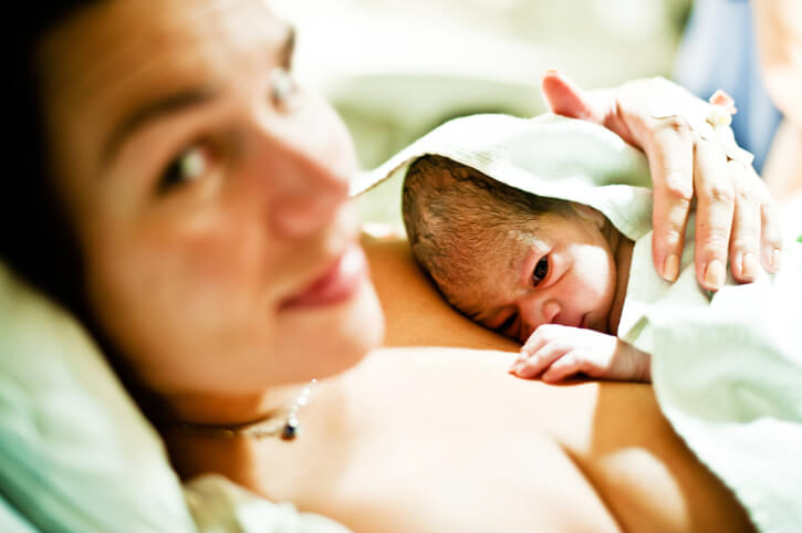 Amning efter kejsersnit - nyfødt på maven af sin mor