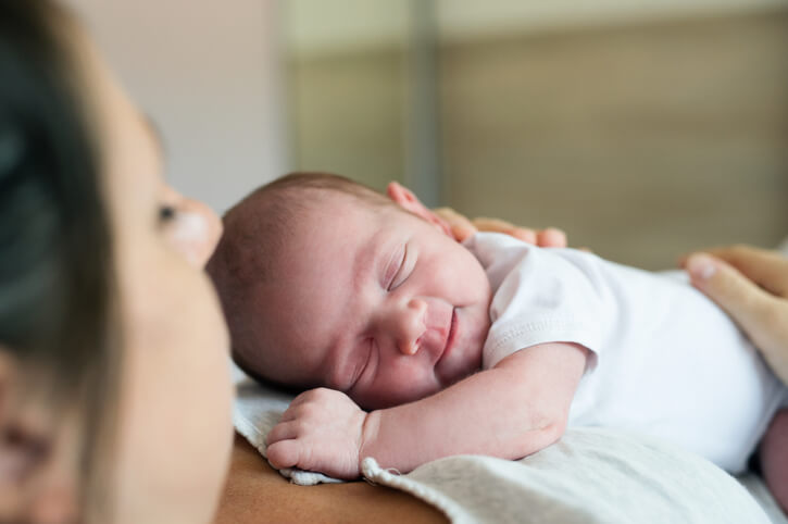 Glad baby der ligge på mors bryst