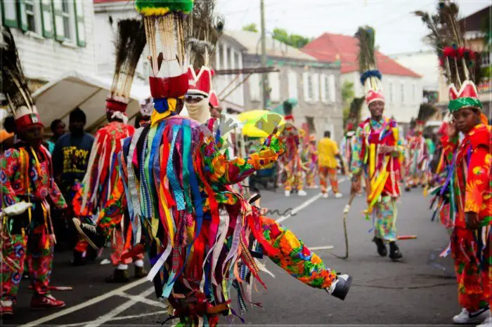 People celebrate in the street in colorful costumes during St Kitts Carnival