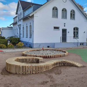 Lamelbænk med indvendig diameter 300 cm og udvendig diameter 400 cm. Én bølge og åbning. Opsat ved kirke på Djursland.