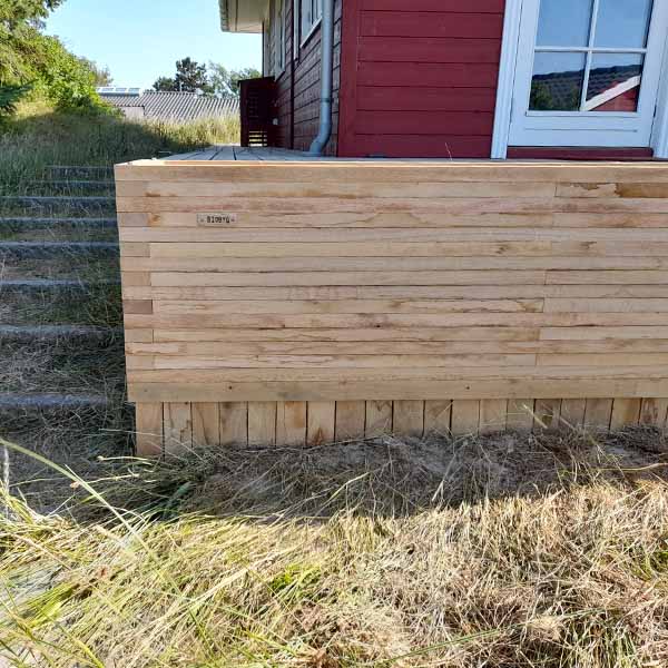 Plantekasse rundt om terrasse ved sommerhus.