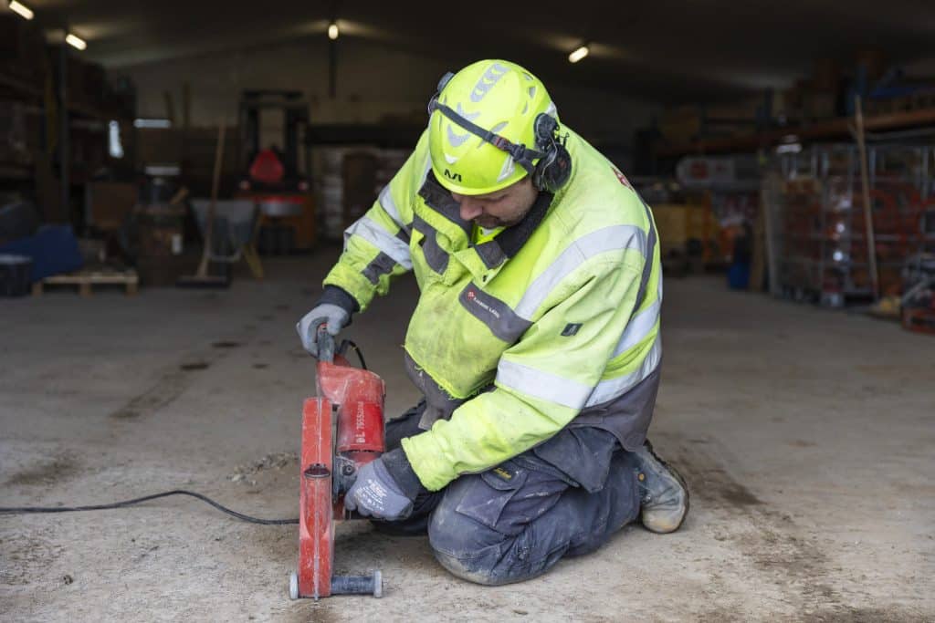 arbejdsmand arbejder med gulvskærer på betongulv