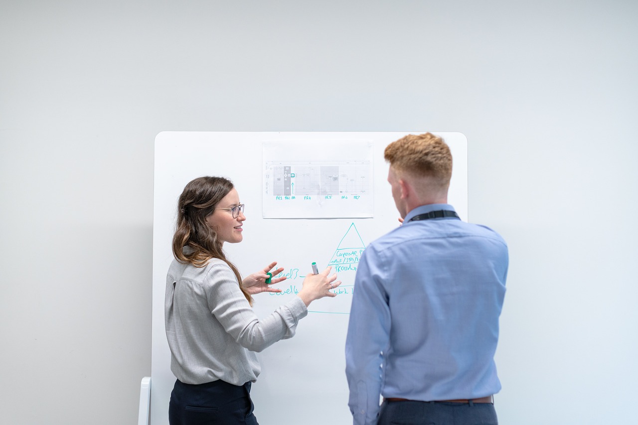 a man and woman standing in front of a whiteboard