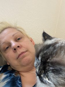 En nedtrykt kvinde, med en kat på brystet, der healer hende
