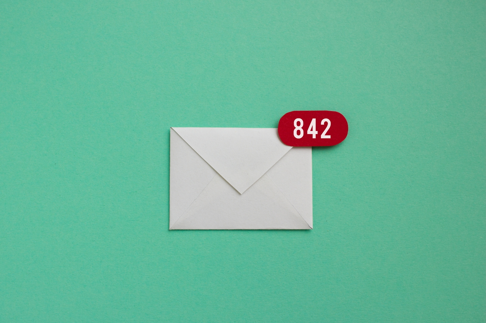 A white paper envelope at the center of a greenpaper. A red notification bubble is at the right upper corner of the envelope. 842 notifications is written on white.