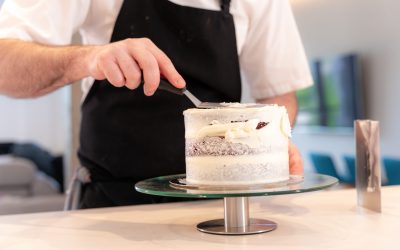 Hands of a man cooking a red velvet cake at home, with the smoothing spatula leaving the perfect circle