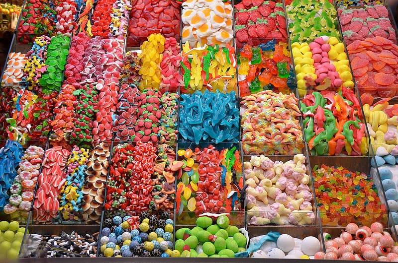 Många färgglada godissorter i plastlådor för att locka barn med sitt socker