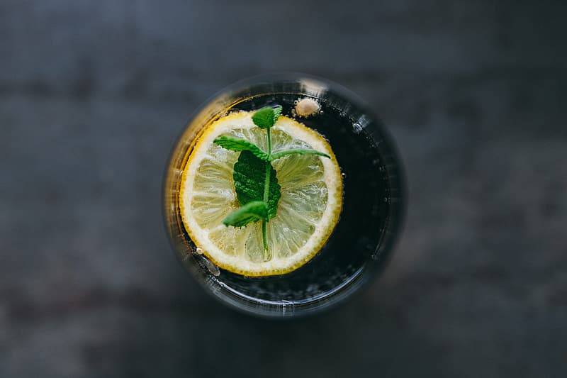 vattenglas med citronskiva och kvist med mynta fotat ovanfrån, drick lagom mycket vätska