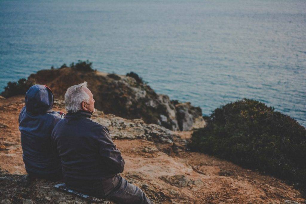 gammalt par sitter tillsammans på klippor framför havet och tittar ut, hälsosamma relationer