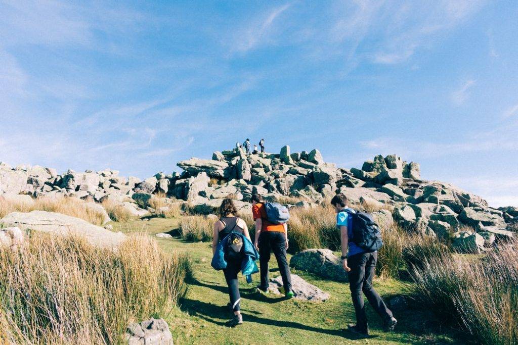 Killar och tjej går på vandring i bergen, hiking som är bra för hälsan 