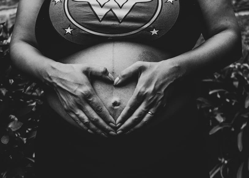 Svartvit bild på gravid kvinna. Bilden är tagen från brösten ner till höfterna. Hon har en topp och bar mage och håller sina händer på magen och formar ett hjärta med fingrarna precis över naveln. Stort behov av järn under graviditet