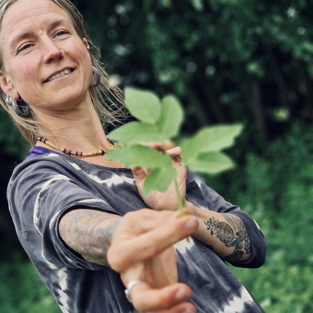 Karoline Karttunen från Karolines way of life visar hur kirskål ser ut under örtvandring. Hon håller fram det gröna bladet med kirskål framför kameran och ler finuerligt