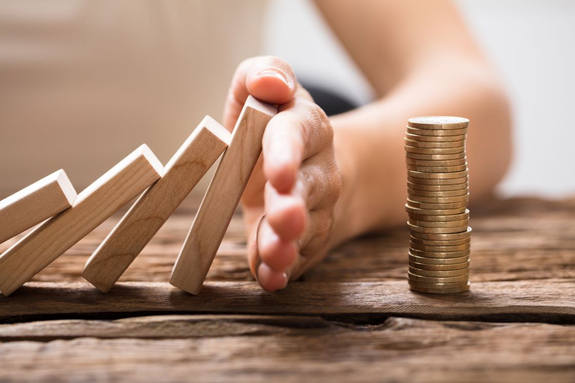 Compliance: a series of dominos being blocked from falling on a stack of coins