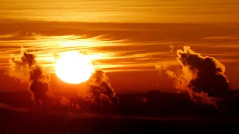 Andrew Milligan/PA Wire A bright sun creates a red sky over the industrial chimney stacks of Grangemouth