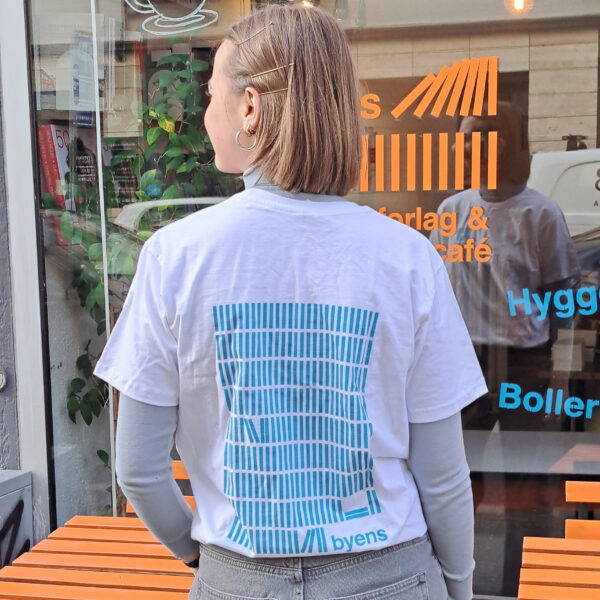 Kvinde set bagfra med hvid t-shirt med blåt tryk af bøger.