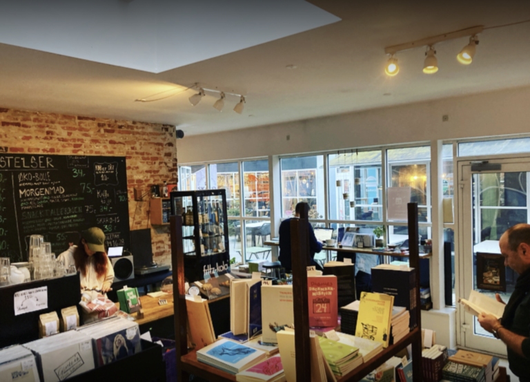 Tre personer indenfor ved Byens Forlags bogcafe i Vejle.
