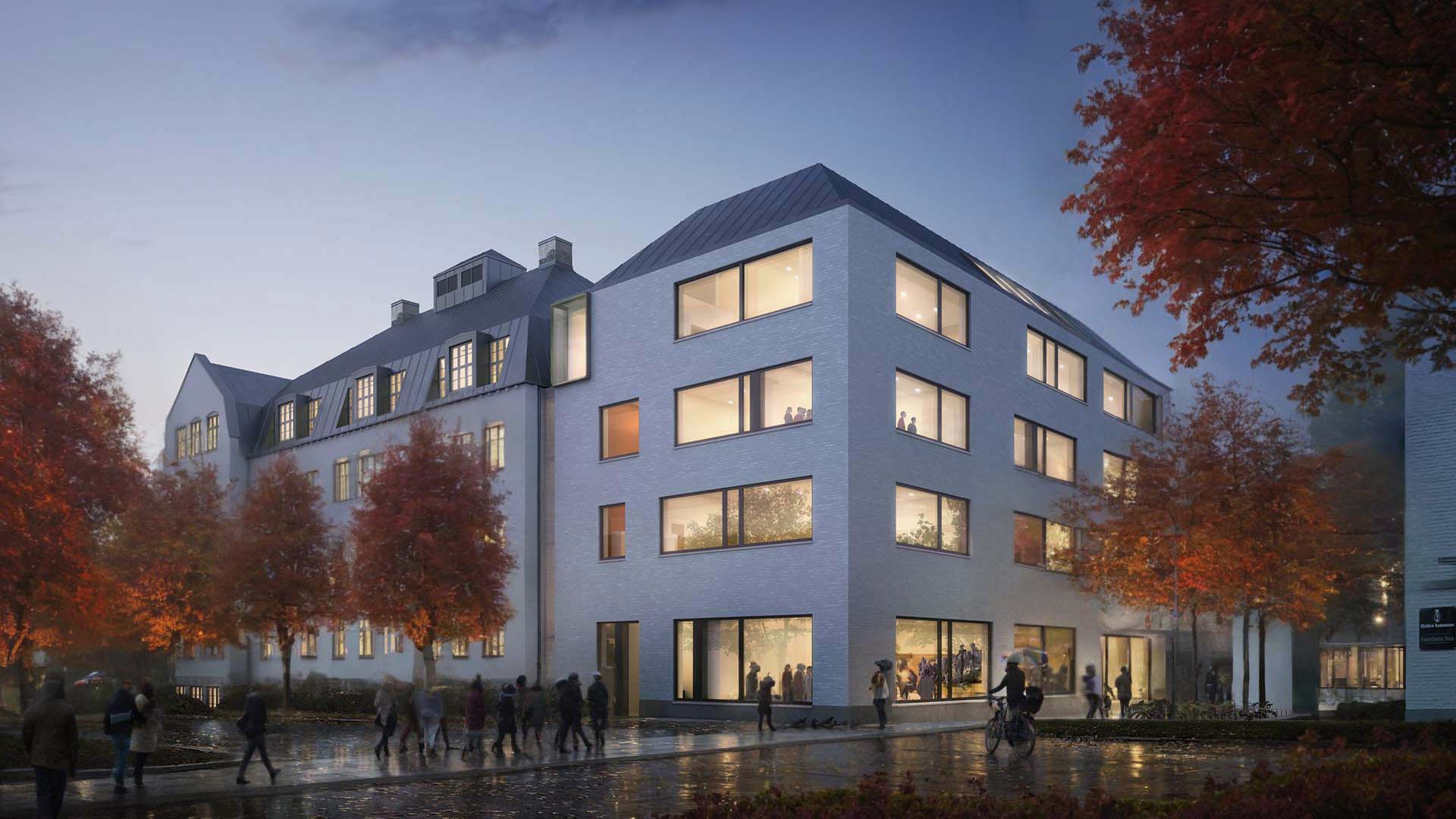 <strong>Os Skole & Halden Arena</strong> Evening exterior of Os Skole & Halden Arena in Norway by Asplan Viak, featuring warm interior lighting and autumn trees in an urban setting.