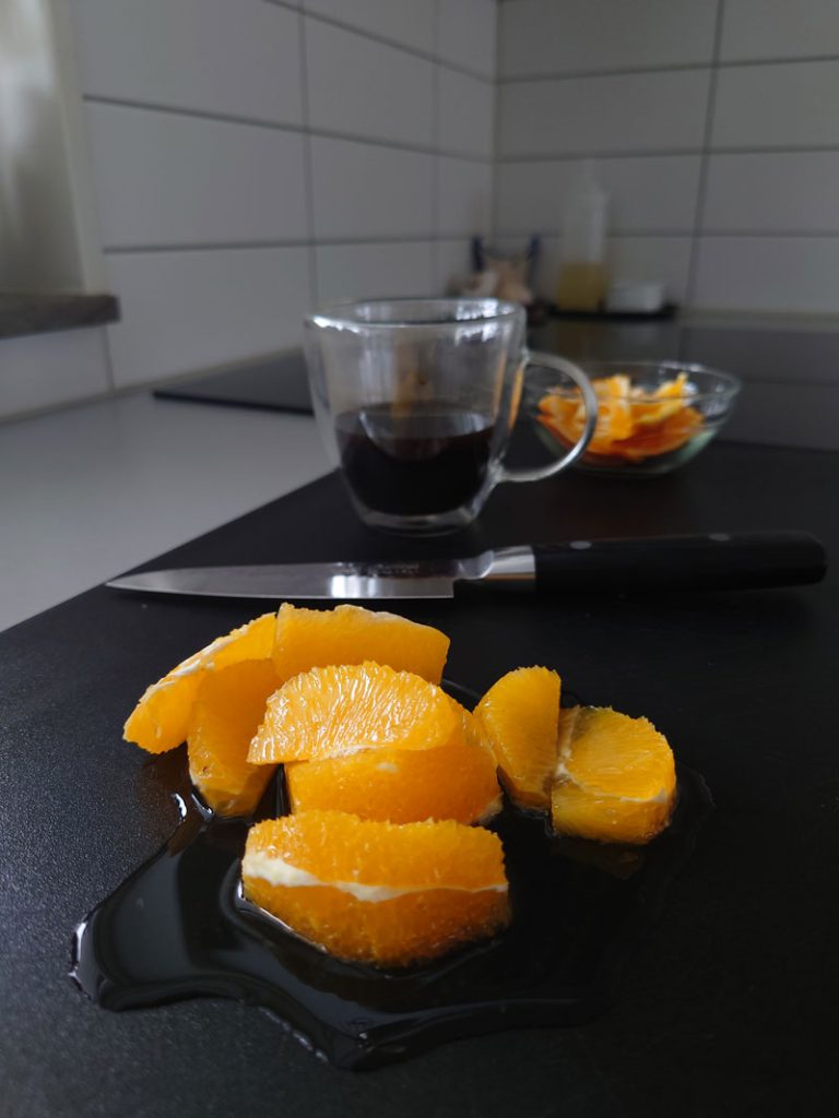 Apelsinklyftor på en skärbräda. En kniv och en kopp kaffe.