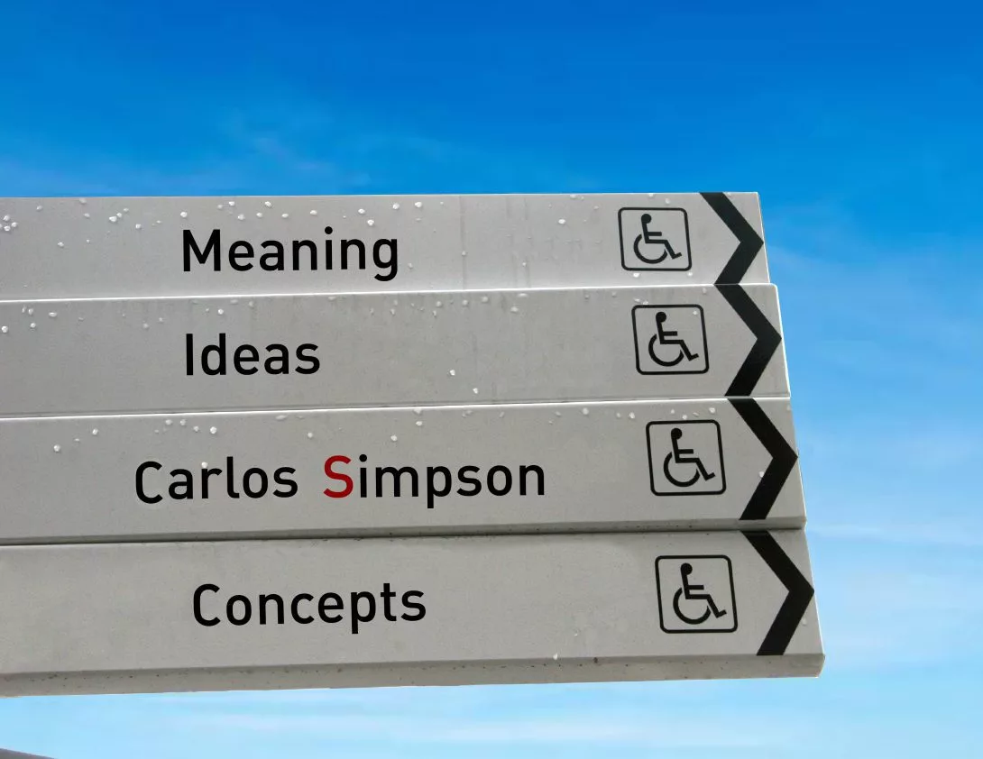 Signpost with words “Meaning,” “Ideas,” “Carlos Simpson,” and “Concepts” against a blue sky, symbolising direction in design thinking.