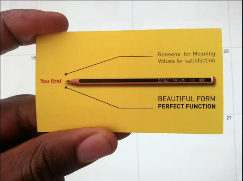 Carlos Simpson Design Studio business card emphasizing values such as "You first", "Beautiful form, perfect function", and "Reasons for meaning, values for satisfaction", with a pencil branded "Carlos Simpson" placed in the center.