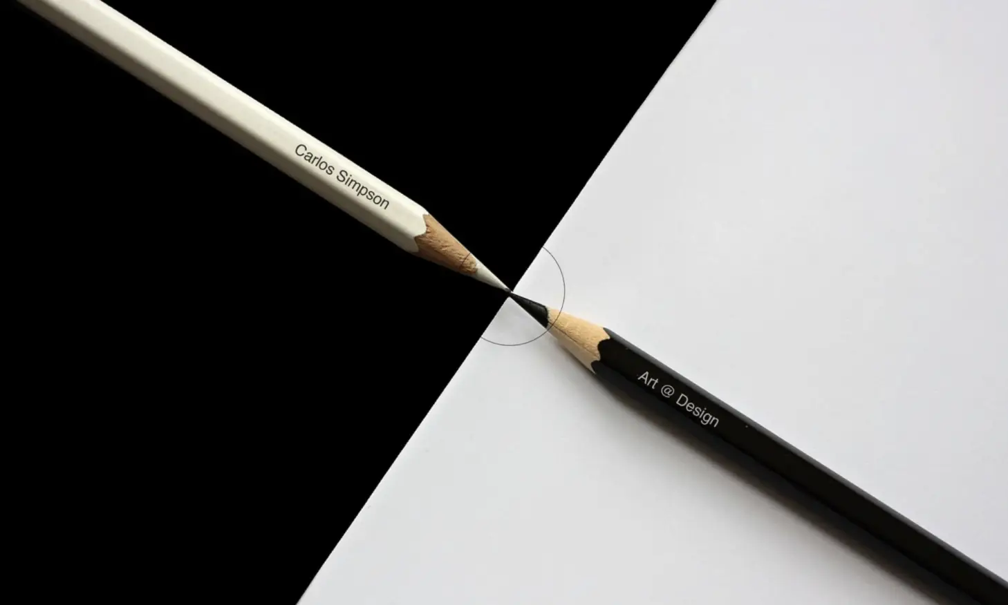 Two sharpened pencils - one white inscribed with “Carlos Simpson” and one black inscribed with “Art @ Design” — meet precisely at their tips, forming a perfect boundary between a black and white background. The image symbolizes balance, creativity, and the seamless integration of art and design. Representing Carlos Simpson Design Studio, the composition highlights core brand values: conceptual precision, minimalist beauty, and the powerful intersection of identity, contrast, and creative innovation.