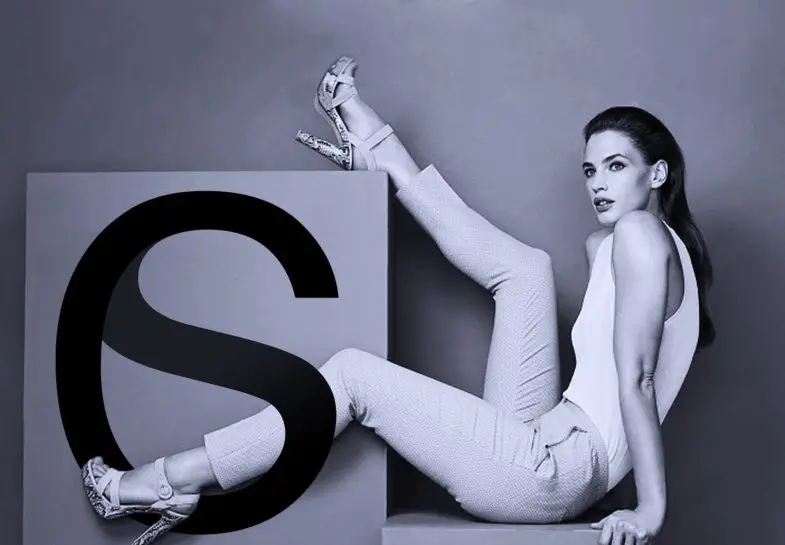 The fashion-forward model poses against a minimalist background with a bold ‘S’ graphic – branding visual by Carlos Simpson Design Studio highlighting elegance, modern typography, and identity-driven design.
