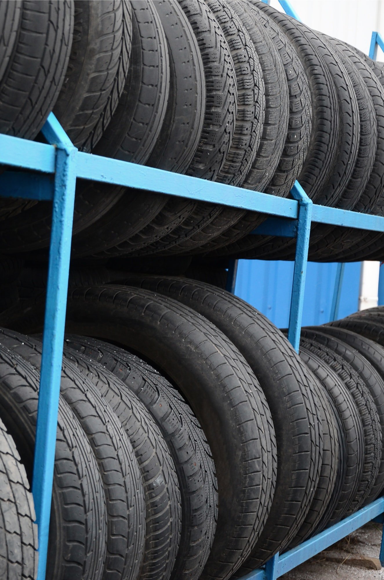 Rack with variety of car tires in automobile store. Many black tires. Tire stack background