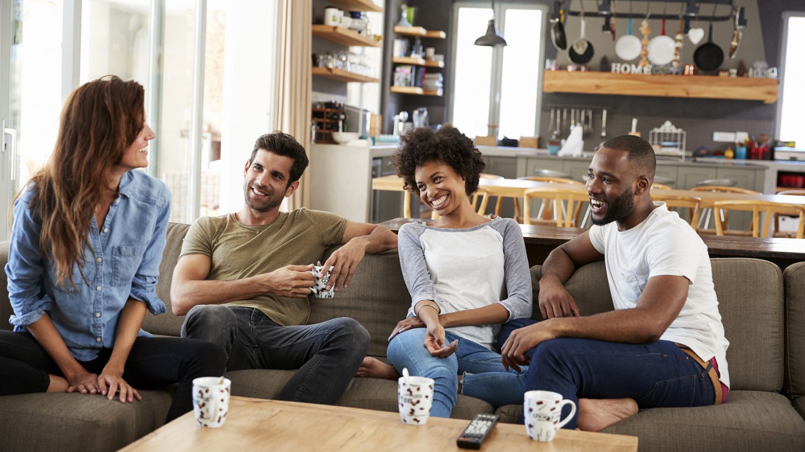 Couple Sitting On Sofa With Friends At Home Talking