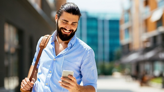 smiling man listening to phone with earphones