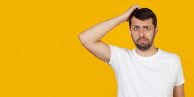 man in white shirt scratching head confused